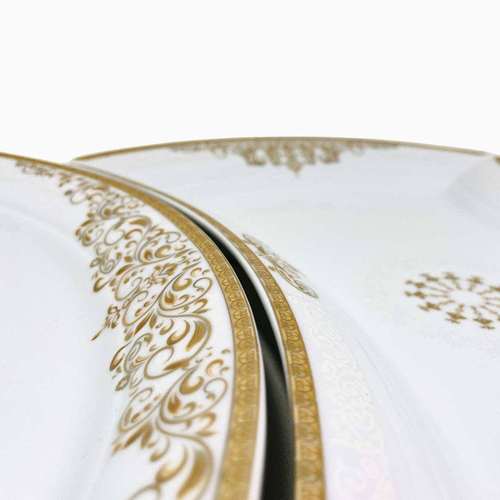 Close-up of a white plate with gold decorative border on a white background