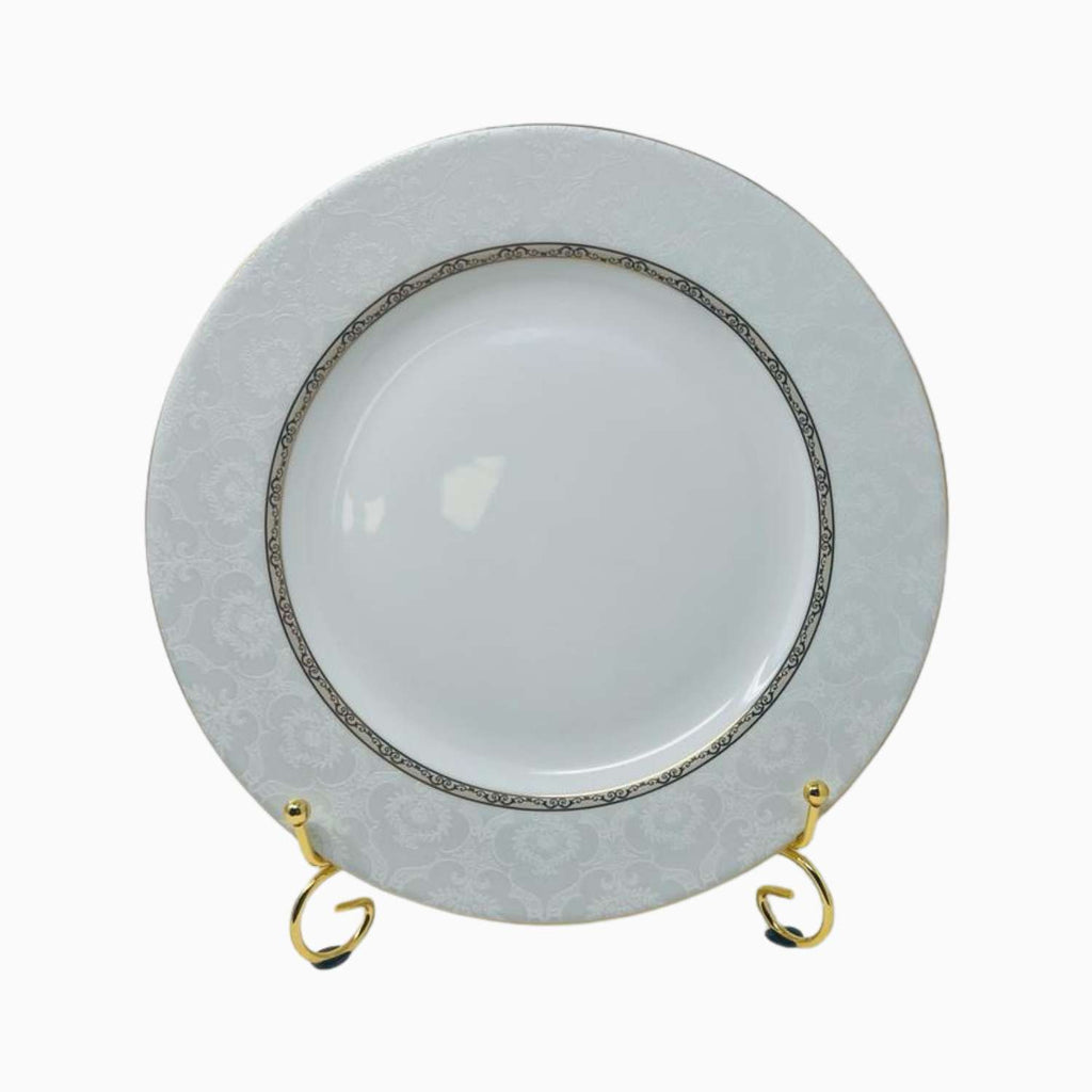 White ceramic plate with decorative rim on a stand against a white background