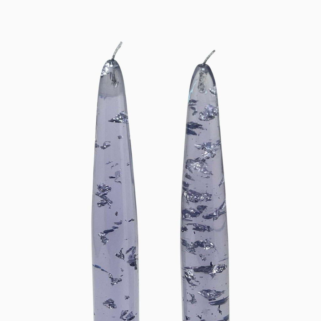 Two tall, slender candles with a floral pattern on a white background