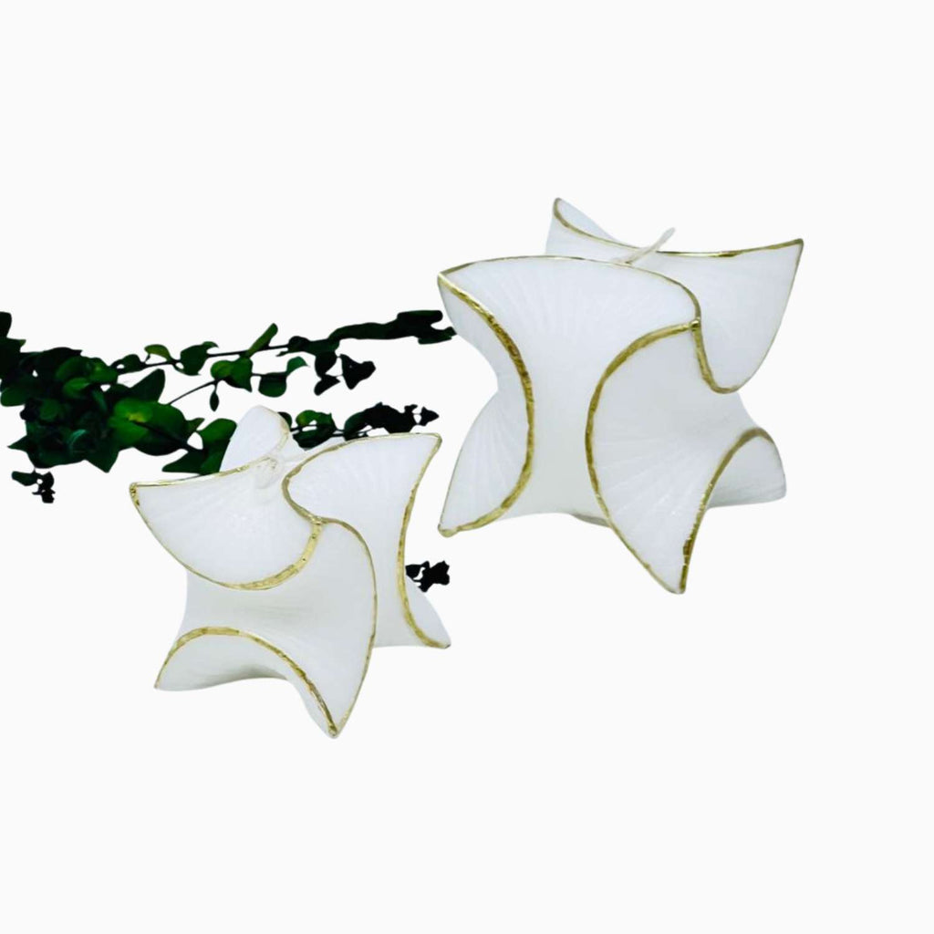 White butterfly-shaped candles with gold accents on a white background