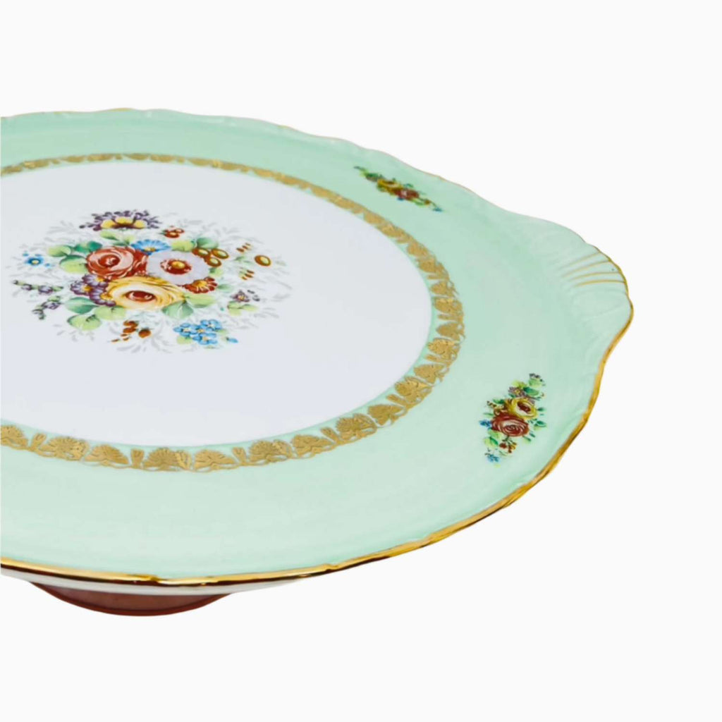 Decorative ceramic plate with floral design and gold trim on a white background