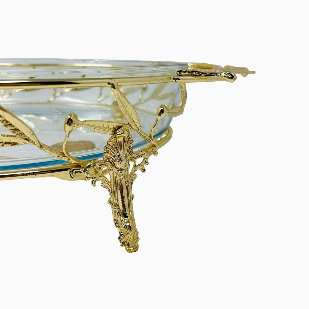 Decorative glass dish with gold rim and intricate design on a white background