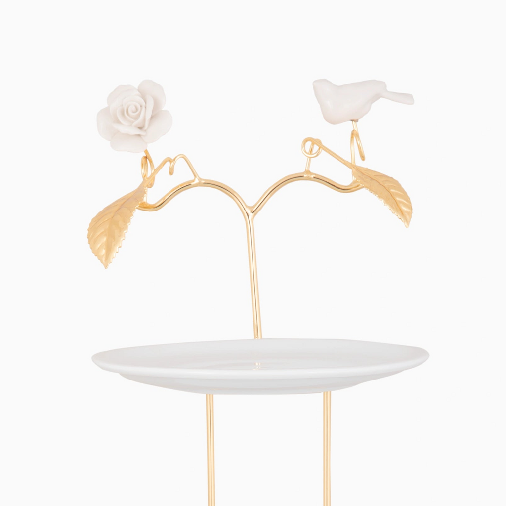 Decorative cake stand with gold accents, white rose, and bird on a white background