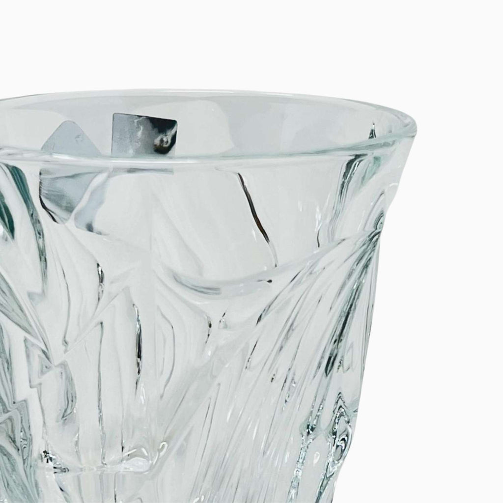 Close-up of a clear glass with intricate cut patterns on a white background