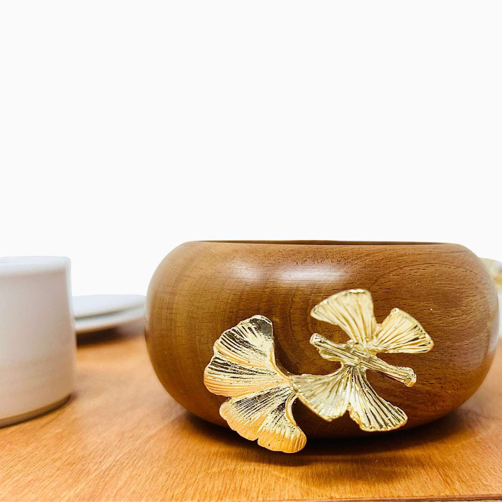 Wooden bowl with gold leaf designs on a wooden surface