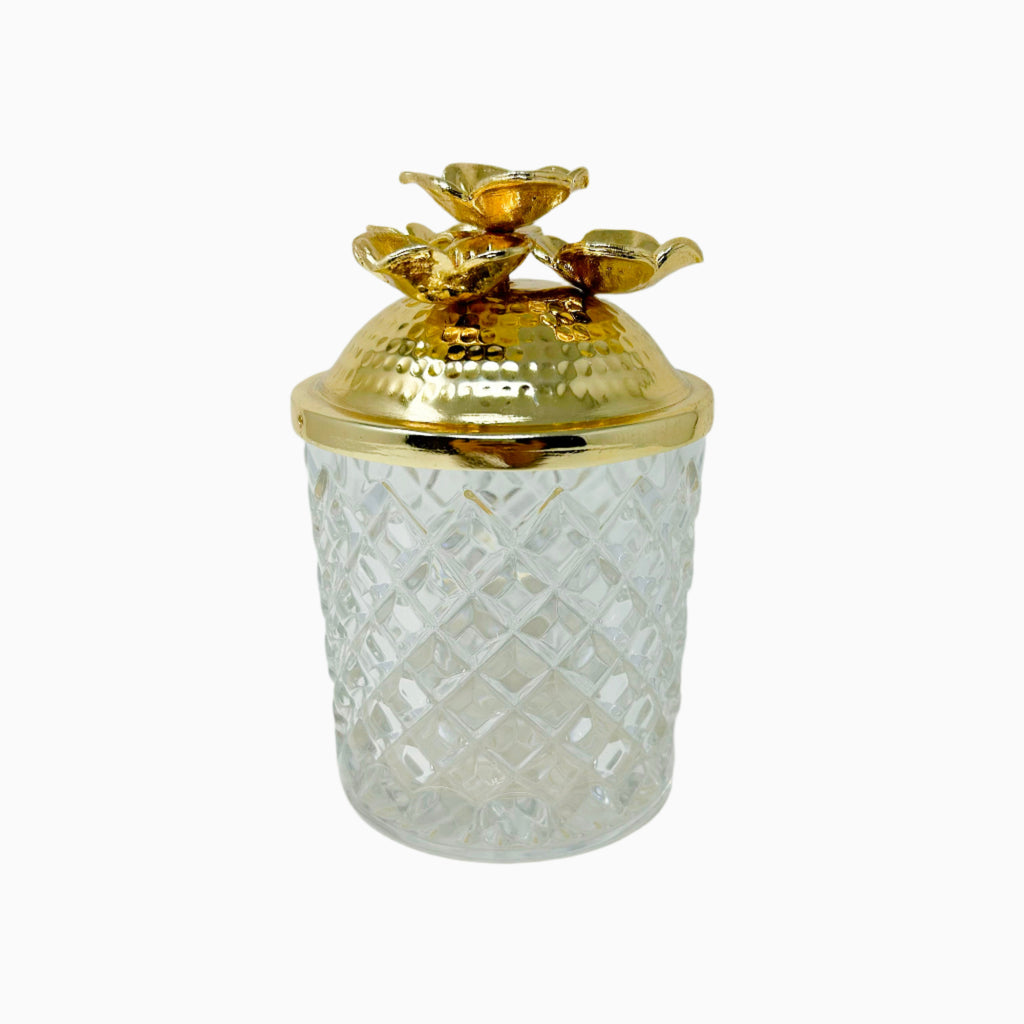 A clear glass jar with a gold-tone lid featuring a floral design on the lid and a matching floral pattern on the jar.