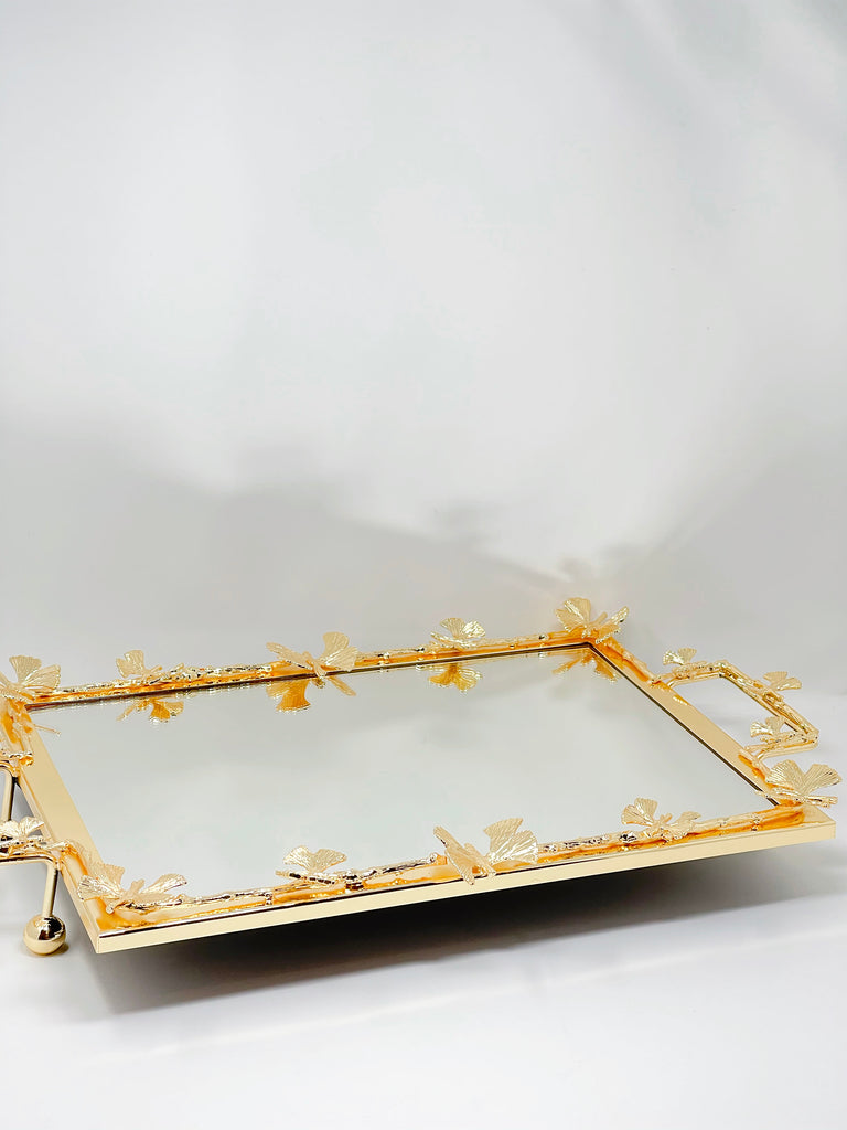 A rectangular mirror tray with a gold frame and butterfly cutouts, perfect for serving or displaying decor