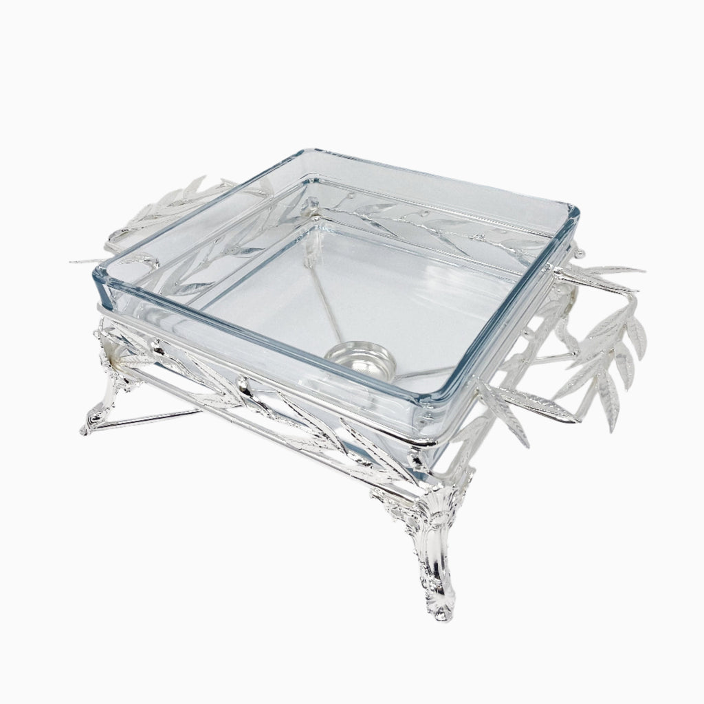 Elegant square glass Pyrex serving dish set in an intricately crafted silver-tone metal stand featuring detailed leaf motifs and sculpted legs. Noble Home Gifts